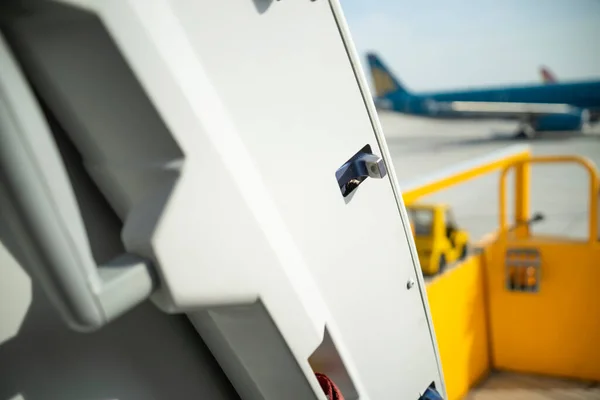 Open door to a large airliner as seen from inside. Aircraft door frame, door handle and door barrier strap. Selective focus.