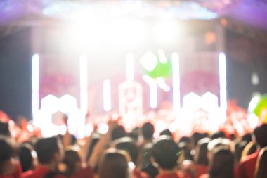 Konser sahnesinin önündeki kalabalık bulanıklaştı. Kalabalığın el kaldırıp bir konsere katıldığı bulanık bir eğlence festivali konseri. Yaz müzik festivali konsepti.