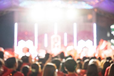 Konser sahnesinin önündeki kalabalık bulanıklaştı. Kalabalığın el kaldırıp bir konsere katıldığı bulanık bir eğlence festivali konseri. Yaz müzik festivali konsepti.