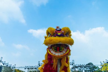 Aslan dansı - ejderha ve aslan sokak gösterileri. Arka planda mavi gökyüzü olan sarı aslan başı. Kültür ve festival konsepti.