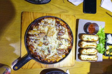 Tokbokki veya Tteokbokki (Baharatlı Pirinç Kekleri) baharatlı tavuk ve fırında kızarmış mozzarella tavukları. Ahşap arka planda geleneksel Kore yemekleri yakın plan. Seçici odak.