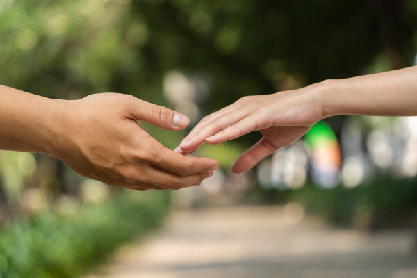 концепция человеческих отношений, общности, единства, командной работы, любви, символизма, культуры и истории. рука мужчины и женщины тянутся друг к другу. природный фон. селективный фокус.