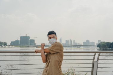 Sosyal uzaklık. Korumalı maskeli genç Asyalı adam dışarıda parkta çalışıyor. Egzersiz yap. Karantinada spor. Covid-19. Korunma. Seçici odak.