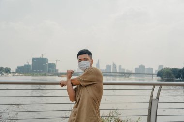 Sosyal uzaklık. Korumalı maskeli genç Asyalı adam dışarıda parkta çalışıyor. Egzersiz yap. Karantinada spor. Covid-19. Korunma. Seçici odak.