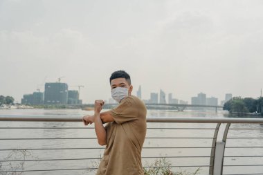 Sosyal uzaklık. Korumalı maskeli genç Asyalı adam dışarıda parkta çalışıyor. Egzersiz yap. Karantinada spor. Covid-19. Korunma. Seçici odak.