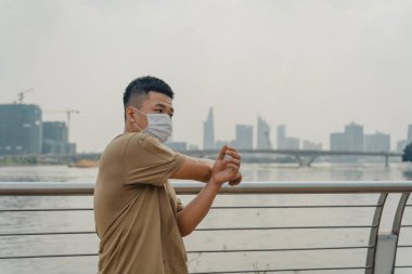 Sosyal uzaklık. Korumalı maskeli genç Asyalı adam dışarıda parkta çalışıyor. Egzersiz yap. Karantinada spor. Covid-19. Korunma. Seçici odak.