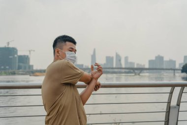 Sosyal uzaklık. Korumalı maskeli genç Asyalı adam dışarıda parkta çalışıyor. Egzersiz yap. Karantinada spor. Covid-19. Korunma. Seçici odak.