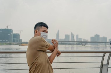 Sosyal uzaklık. Korumalı maskeli genç Asyalı adam dışarıda parkta çalışıyor. Egzersiz yap. Karantinada spor. Covid-19. Korunma. Seçici odak.