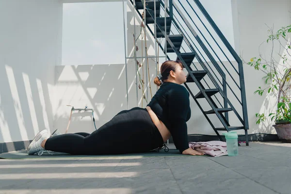 Sağlık, fitness ve spor konsepti. Artı boy Asyalı bir kadın balkonda egzersiz yapıyor, evde fazladan kilo verecek, güçlü ve zinde olacak, antrenman dayanıklılığı kazanacak. Sosyal uzaklık.
