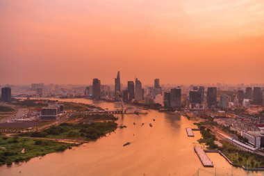 Ho Chi Minh şehri, Vietnam - 6 Nisan 2021: Ho Chi Minh şehrinin havadan görünüşü, Vietnam. Nehir ışığı boyunca uzanan güzel gökdelenler şehir gelişimini yumuşatır. Dramatik ışıklandırma muhteşem gün batımı.