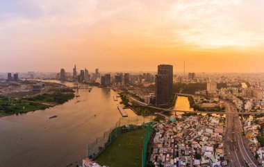 Ho Chi Minh şehri, Vietnam - 6 Nisan 2021: Ho Chi Minh şehrinin havadan görünüşü, Vietnam. Nehir ışığı boyunca uzanan güzel gökdelenler şehir gelişimini yumuşatır. Dramatik ışıklandırma muhteşem gün batımı.