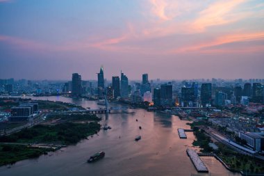 Ho Chi Minh şehri, Vietnam - 6 Nisan 2021: Ho Chi Minh şehrinin havadan görünüşü, Vietnam. Nehir ışığı boyunca uzanan güzel gökdelenler şehir gelişimini yumuşatır. Dramatik ışıklandırma muhteşem gün batımı.