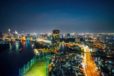 Ho Chi Minh şehri, Vietnam - 6 Nisan 2021: Ho Chi Minh şehrinin havadan görünüşü, Vietnam. Nehir ışığı boyunca uzanan güzel gökdelenler şehir gelişimini yumuşatır. Dramatik ışıklandırma muhteşem gece.