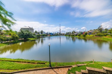 Bao Loc şehri, Vietnam - 01 Mayıs 2021: Küçük Dong Nai Gölü manzarası - Bao Loc şehrinin merkezi gölü, Lam Dong eyaleti, Vietnam. Büyük bir televizyon kulesinin yanında güzel duruyor..