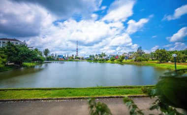 Bao Loc şehri, Vietnam - 01 Mayıs 2021: Küçük Dong Nai Gölü manzarası - Bao Loc şehrinin merkezi gölü, Lam Dong eyaleti, Vietnam. Büyük bir televizyon kulesinin yanında güzel duruyor..