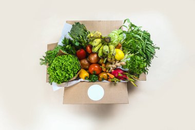 Close-up of fresh vegetables in cardboard box on the table delivered to home, donation box with supplies food for people, vegetables and fruit in cardboard box. Selective focus.