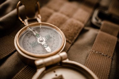 Taktik ya da seyahat çantasındaki altın pusula, sığ DOF, kadranlara odaklan. Yönlendirme, seyahat, rehberlik ya da yardım kavramı. Seçici odak.