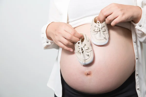 Маленькая обувь для будущего ребенка во чреве беременной женщины — стоковое фото