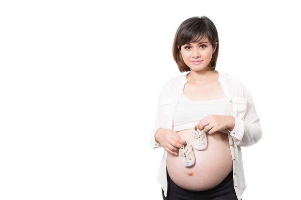 Мама держит маленькие ботинки для нерожденного ребенка в животе беременной — стоковое фото