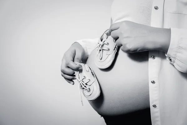 Маленькая обувь для будущего ребенка во чреве беременной женщины — стоковое фото