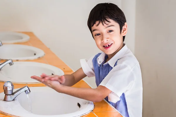 Piccolo ragazzo lavarsi la mano con il viso sorridente Foto Stock
