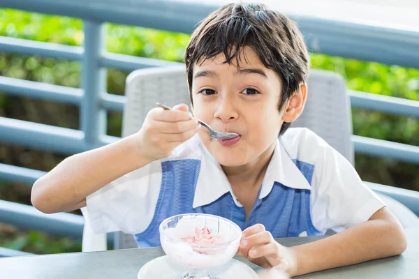 Niño comiendo helado con la cara sonriente Imagen de stock