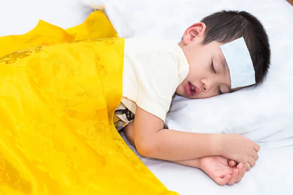 Piccolo asiatico ragazzo ha febbre e dormire su letto con gel febbre su h Immagine Stock