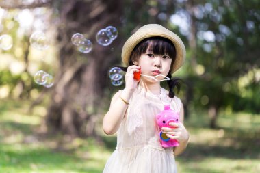 Asyalı küçük kız p gülümsemek yüz sabun köpüğü üfleme