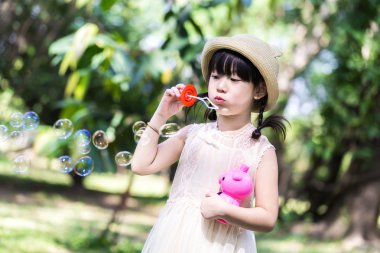 Asyalı küçük kız p gülümsemek yüz sabun köpüğü üfleme