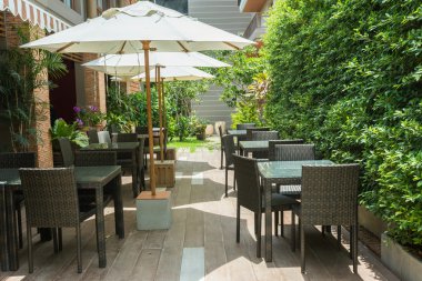 Cafe masa ve sandalyeler dışında büyük beyaz şemsiye ve bitki ile