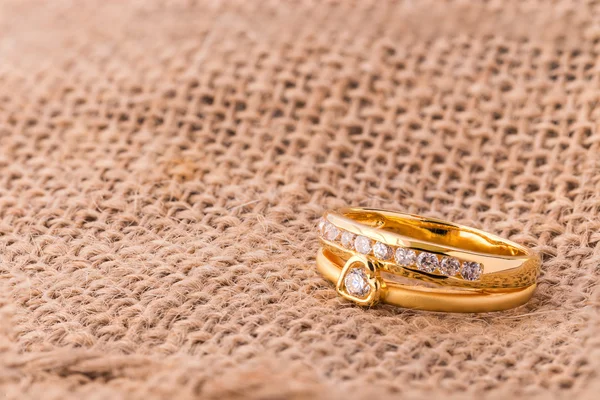 Tvar srdce diamantový prsten na pytlovina zkřížili plenit textury — Stock fotografie
