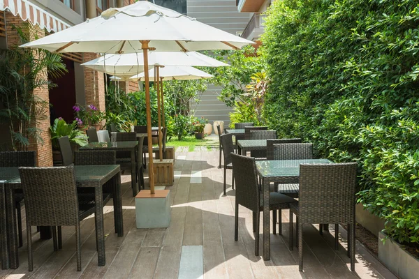 Cafe masa ve sandalyeler dışında büyük beyaz şemsiye ve bitki ile