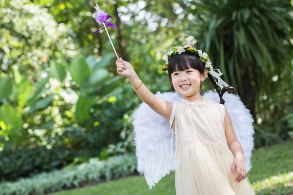 Niña linda en vestido de ángel con la cara sonriente en el parque Imagen de archivo