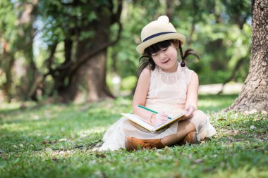 Küçük Asyalı kız defter üzerinde yazma kalem kullanın