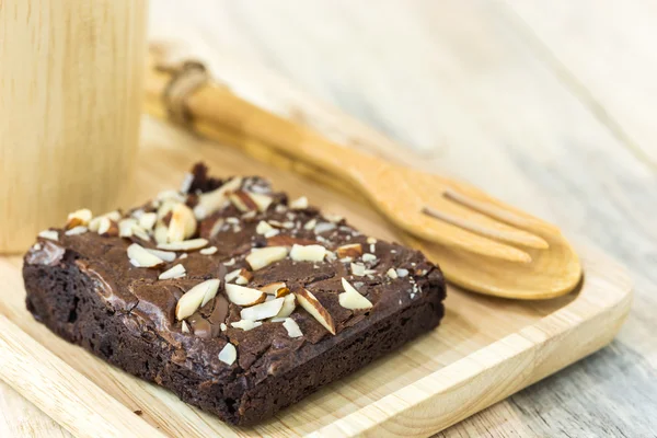 Brownie na dřevěné desce s dřevěnými hrnek na dřevěné prkenné zdi — Stock fotografie