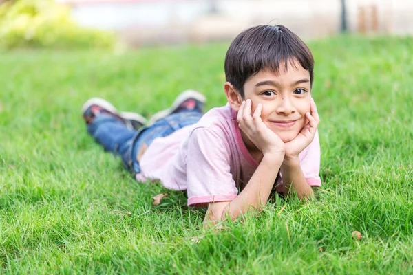 Little boy lay down on the grass with smiling face