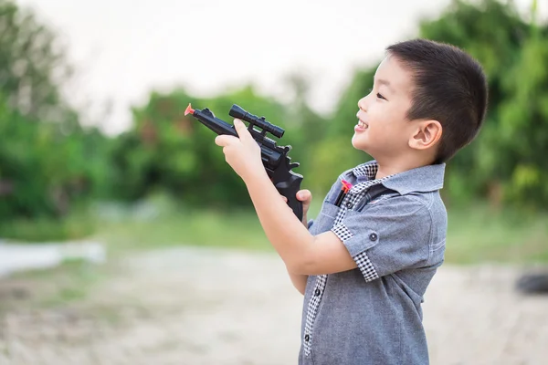 Pequeño asiático chico jugando con un juguete pistola — Foto de Stock