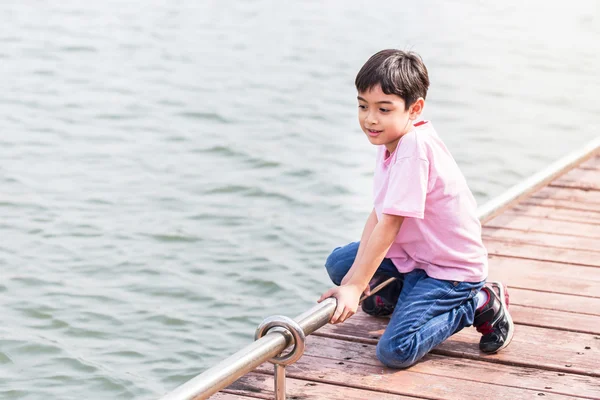 Pequeño asiático chico sentarse en waterfront — Foto de Stock