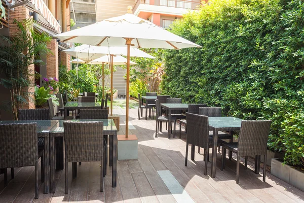 Mesas y sillas de café al aire libre con gran sombrilla blanca y planta Imagen de stock