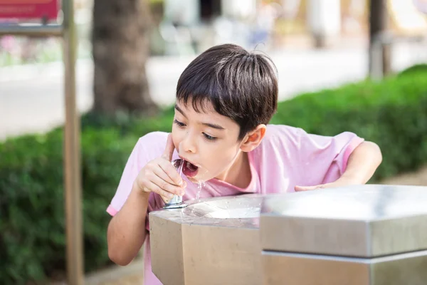 Kleiner Junge trinkt Wasser im öffentlichen Park lizenzfreie Stockfotos