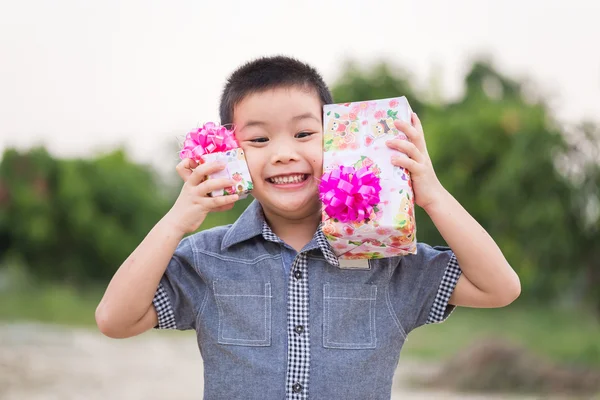 Bambino asiatico che tiene in mano la scatola regalo di Natale Immagine Stock