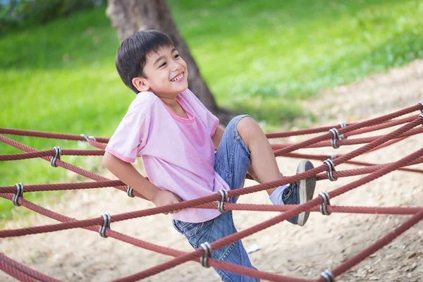 Pouco asiático menino escalada corda obstáculo atividade no playgrou Imagem De Stock