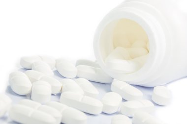 Beyaz tıp hapları bir ilaç şişesi dışarı dökülmesini