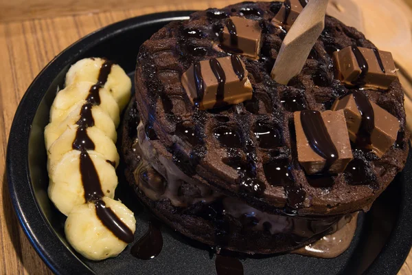 Chocolate waffles with wafer banana and chocolate syrup on wood — Stock Photo, Image