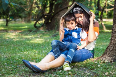 Anne oğlu ile park ağacının altında bir kitapta korumak