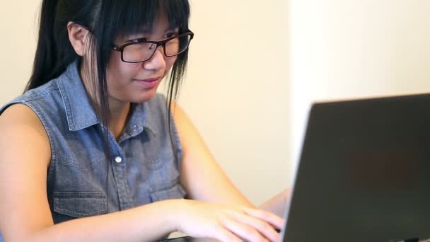 Aziatische vrouw bril zit op stoel thuis en ze werken op een laptop — Stockvideo