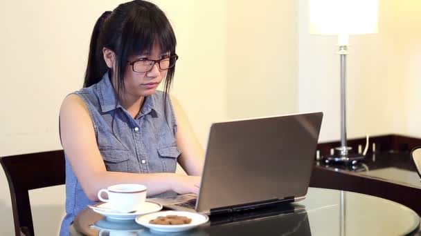 노트북에 그녀 작품과 가정에서 자에 앉아 안경을 착용 하는 아시아 여자 — 비디오