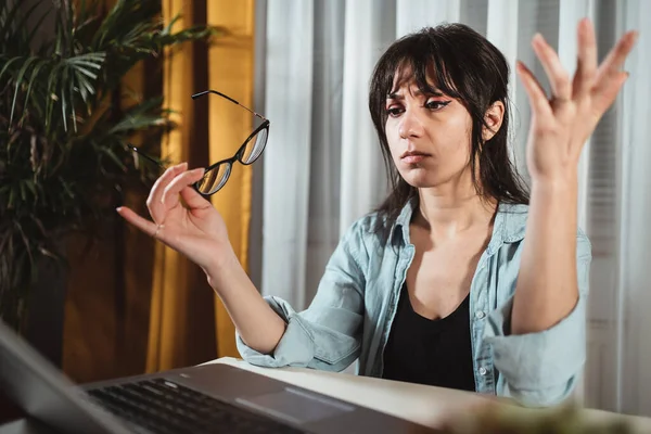 Annoyed young woman with disgust look at laptop screen. Outraged by computer problem or system error, poor internet connection, broken laptop, read bad news or spam email