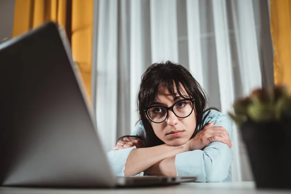 Distracted from work worried young woman sitting at home desk with laptop, thinking of problems. Pensive unmotivated lady looking away, feeling lack of energy, doing remote freelance tasks at home.