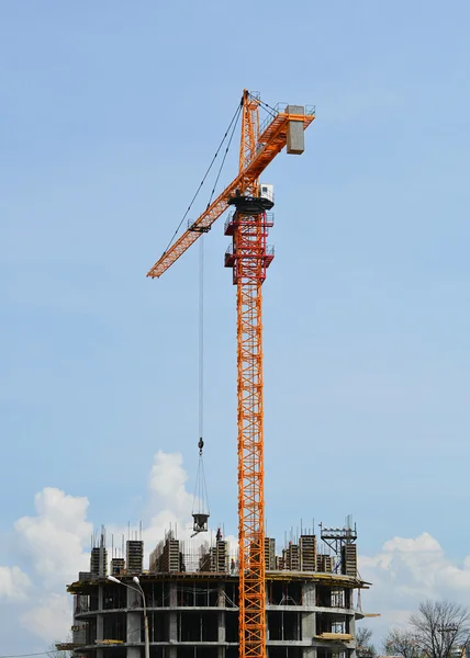 Construction crane lifts materials to the object under construction — Stock Photo, Image